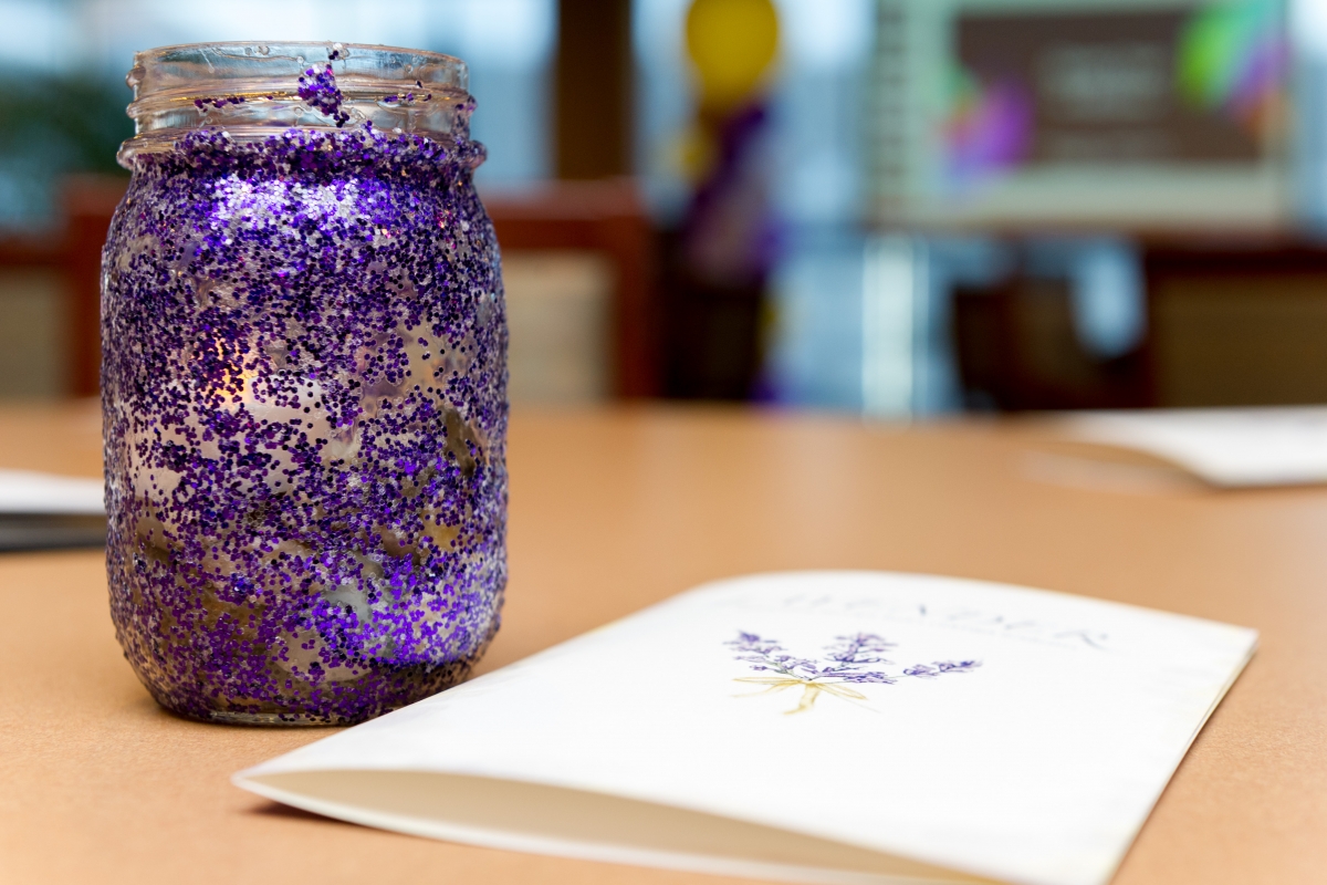 A glass with lavender petals and a note on top of a table.